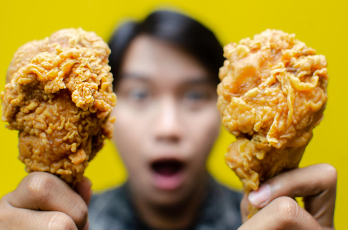 hungry-man-holds-not -fried-chicken-ice-cream -isolated-yellow-background